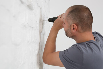 Young man drilling hole in wall 