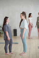 Happy young female trainer talking to girl with Down syndrome during consultation after yoga training