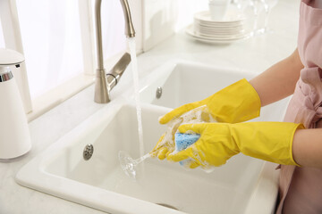 Woman washing glass in modern kitchen, closeup