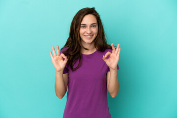 Young caucasian woman isolated on blue background showing ok sign with two hands