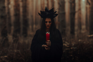 black terrible witch holds candles in her hands