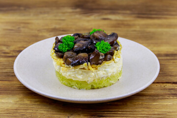 Tasty layered salad with roasted mushrooms, potato, eggs, cheese and mayonnaise on wooden table