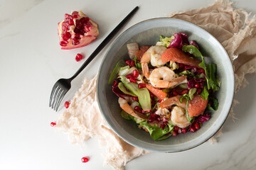 flat lay plate of shrimp, grapefruit, avocado and pomegranate salad on light marble table