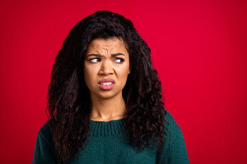 Photo of disgusted unhappy dark skin young woman look empty space dislike face isolated on red...