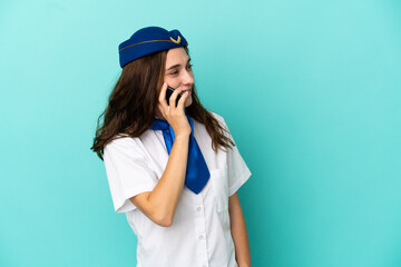 Fototapeta premium Airplane stewardess woman isolated on blue background keeping a conversation with the mobile phone with someone