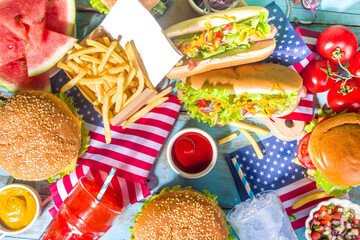 Fourth of July, Memorial Day, USA Independence Day concept. Patriotic, American traditional food. Picnic party with watermelon, burgers, hot dogs, drinks, blue wooden outdoor table background 