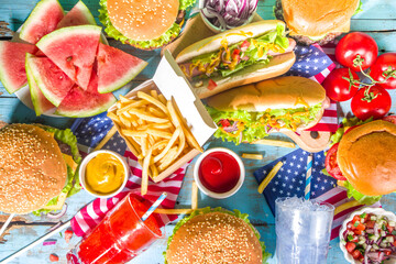 Fourth of July, Memorial Day, USA Independence Day concept. Patriotic, American traditional food. Picnic party with watermelon, burgers, hot dogs, drinks, blue wooden outdoor table background 