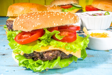 Assorted traditional American burgers, with sauces and fries on a wooden blue background. Picnic, outdoor food background, copy space top view