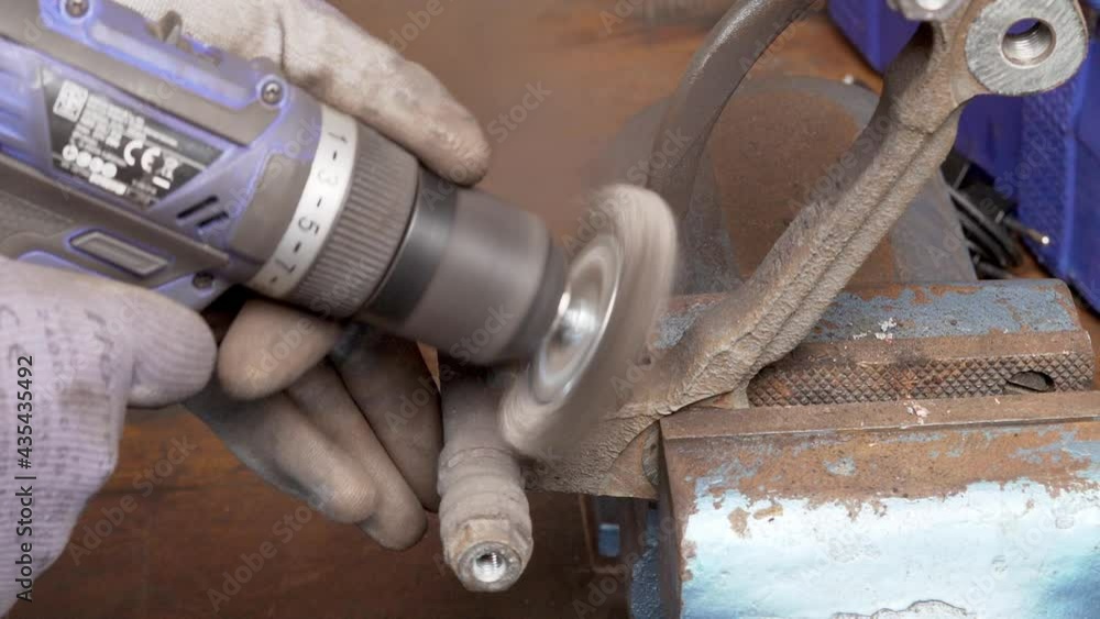 Poster removing rust of a brake caliper mount using circular wire brush at an auto shop. close up