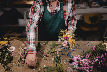 Florist arranging a bouquet of flowers in front of a table with tools