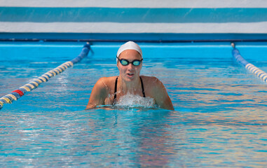 young beautiful woman with swimsuit swimming on a blue water pool