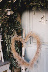 Wooden door decorated with a frame of plants and a wreath of pampas feather