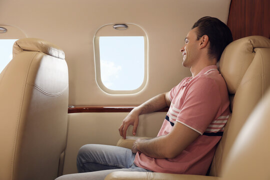 Young Man Looking Out Window In Airplane During Flight