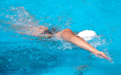young beautiful woman with swimsuit swimming on a blue water pool
