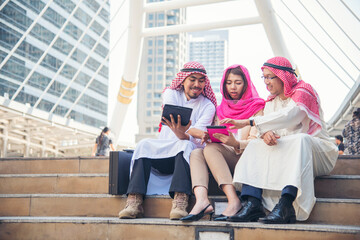 Digital marketing group arab people using smart tablet walking in  modern muslim UAE city touch screen discussion. Entrepreneur Asian people smile talking with boss outdoors