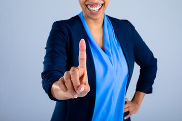 Mid section of businesswoman smiling while touching invisible screen against grey background