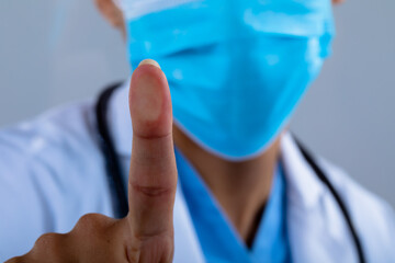 Close up of doctor wearing face mask touching invisible screen against grey background