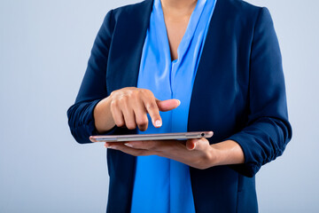 Mid section of businesswoman using a digital tablet against grey background