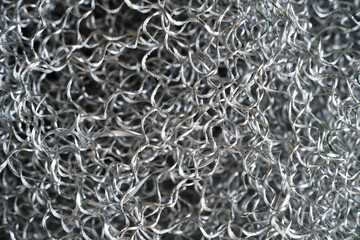 Aluminum chip waste after machining metal parts on a cnc lathe. Closeup twisted spiral steel shavings. Small roughness sharpness,