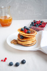 Freshly cooked delicious pancakes with honey, walnut, raspberries and blueberries for breakfast.