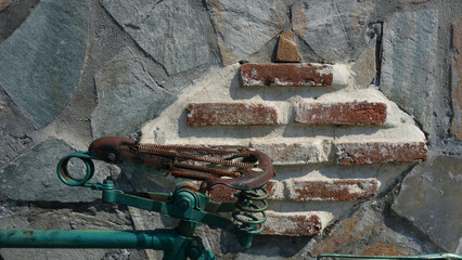 Detail of an old, rusty bicycle against a brick and marble wall background in Vathi, Avlida, Greece