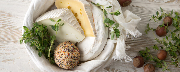 different types of cheese, nuts and thyme on a light table