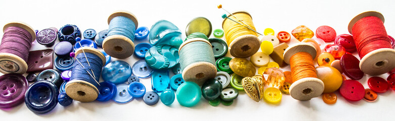 Banner with a lot of buttons and reels with colorful threads, laid out on a white background in the...