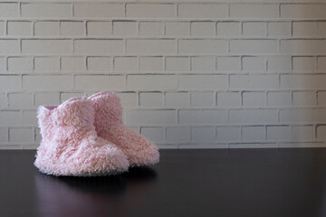 pink fluffy slippers with white tup in front of the wall and on a black background