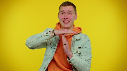 Fototapeta premium Tired serious upset teen stylish boy showing time out gesture, limit or stop sign, no pressure, i need more time. Young man on yellow studio background. People sincere emotions lifestyle concept