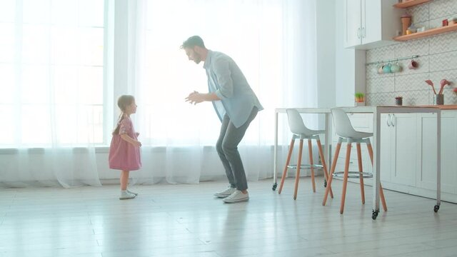 Dancing young father and little preschool girl in the living room. Cute princess and her daddy in the room