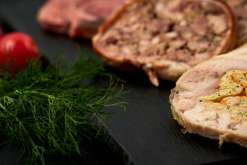 sliced ​​meat rolls with herbs on a black background