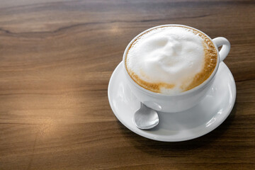 Hot coffee cappuccino latte spiral foam on dark wooden background, hot coffee with foam milk