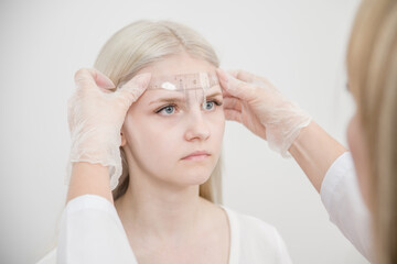 Naklejka premium Young woman having eyebrow correction procedure in beauty salon