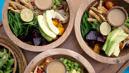 Top view of raw vegan salads served in wooden bowls.
