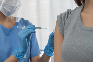Covid-19,coronavirus hand of young woman nurse,doctor giving syringe vaccine, inject shot to asian...