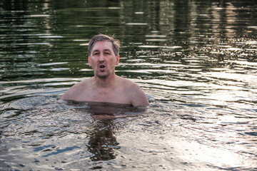 A man swimming in a river in summer.