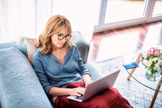 Woman using her laptop while relaxing at home