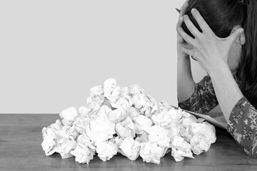 Woman at workplace and crumpled paper pile. Desperate woman submerged from work in her office,...