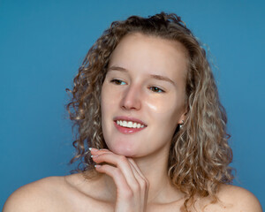 A girl with curly hair touches her chin with her hand, cosmetic patches to eliminate dark circles under the eyes