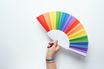 LGBTQ community pride. Hand holds. rainbow fan. Ribbon with rainbow design on wrist. Flat lay, top...