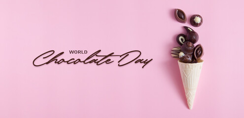 Delicious chocolate pralines in waffle cone on pink background with inscription World Chocolate Day