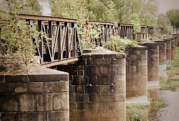 Naklejka premium Old iron railroad bridge with round supporting pillars in the river Elbe in Magdeburg, Germany