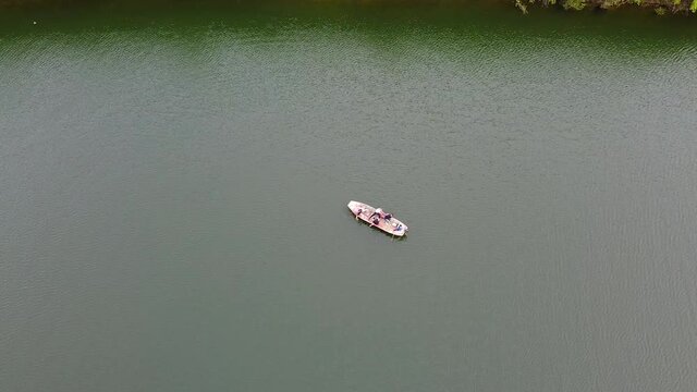 Motor boat broke down in the middle of the lake and people row with hands. Aerial view