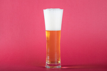 glass of beer before red background, foam and golden color