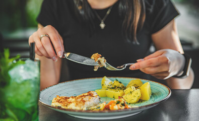 woman hand holding fork and knife eat chicken breast meat with potato in a plate 