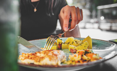 woman hand holding fork and knife eat chicken breast meat with potato in a plate 