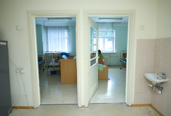 Doors wide opened, two hospital rooms, beds and silhouettes of patients visible
