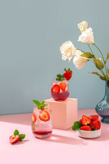 Strawberry Mojito on blue background and pink podium. Refreshing summer drink with copy space