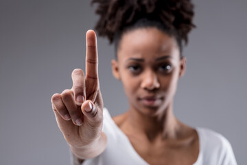 Stern focused young woman holding up her index finger