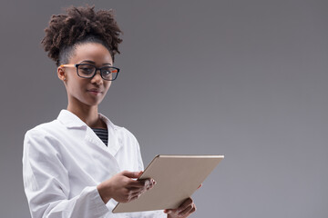 Confident young woman in a white lab coat with tablet-pc